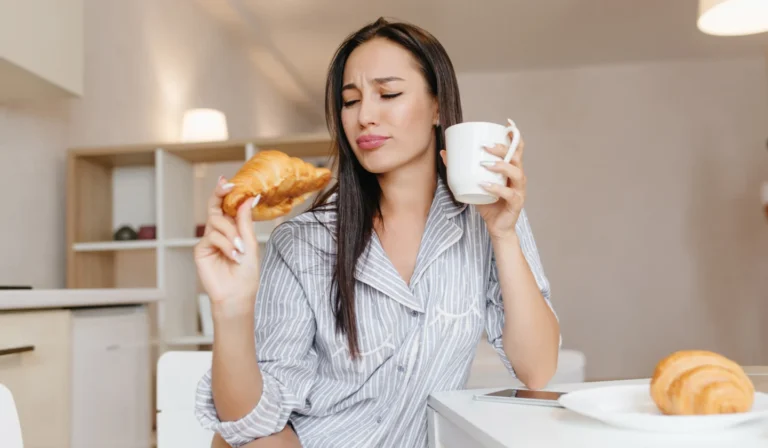 woman in robe enjoying croissant and coffee