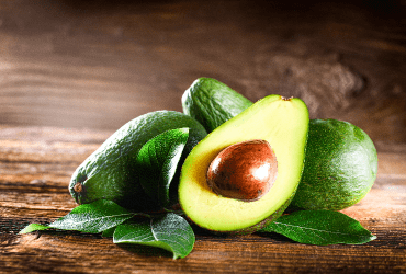 Halved ripe avocado with seed on wood