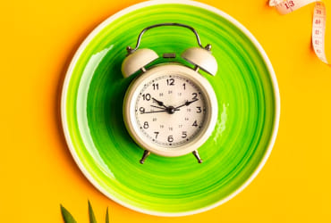 Green alarm clock on bright yellow backdrop