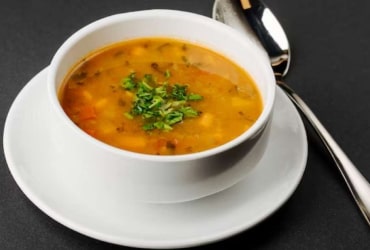 Close-up bowl of rich tomato soup with herbs