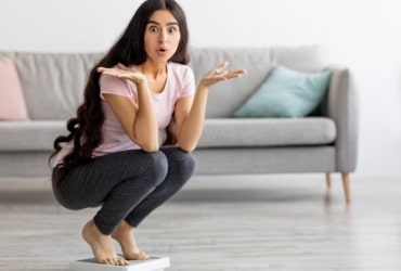 Person in black on couch holding cup in modern room