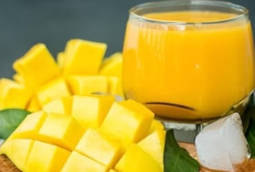 Orange juice and sliced mango on wood