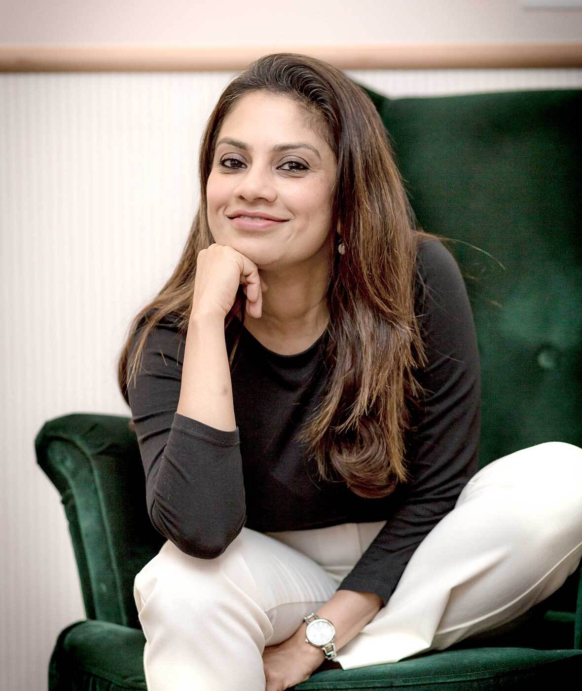 Person in dark sweater on green chair, chin in hand